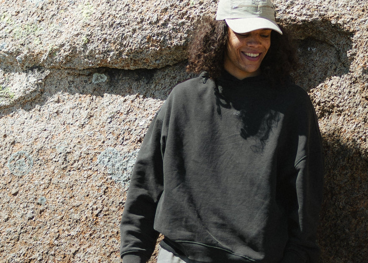 Hvasser — leaning on warm granite in the Pirate Black Project Hoodie (the email A hero; crop from y=440, the top of the