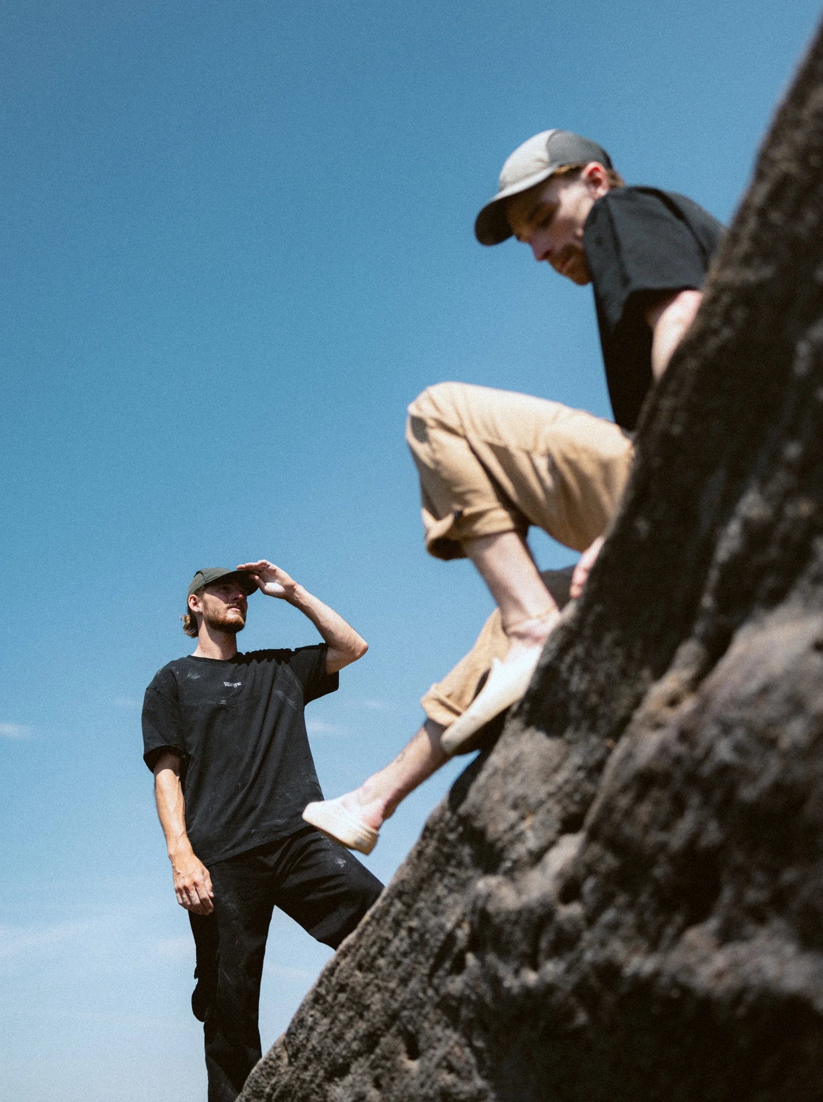 Two climbers on a gritstone arête against a deep blue sky.